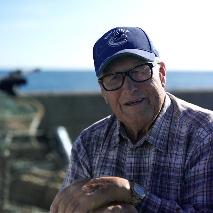 Fisherman sat on the quay side next to lobster pots