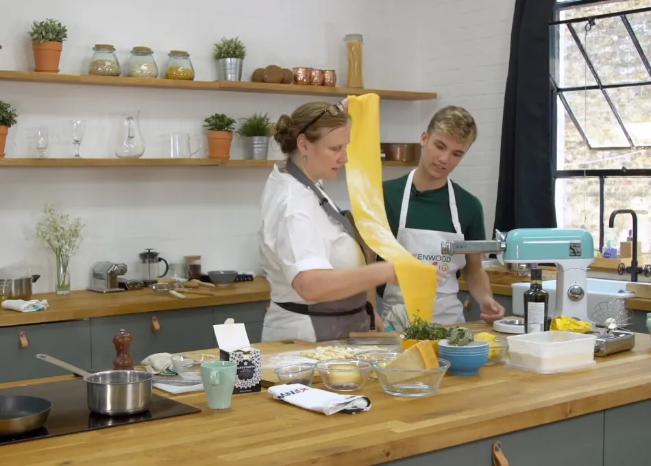 Professional chef showing young adult how to make pasta
