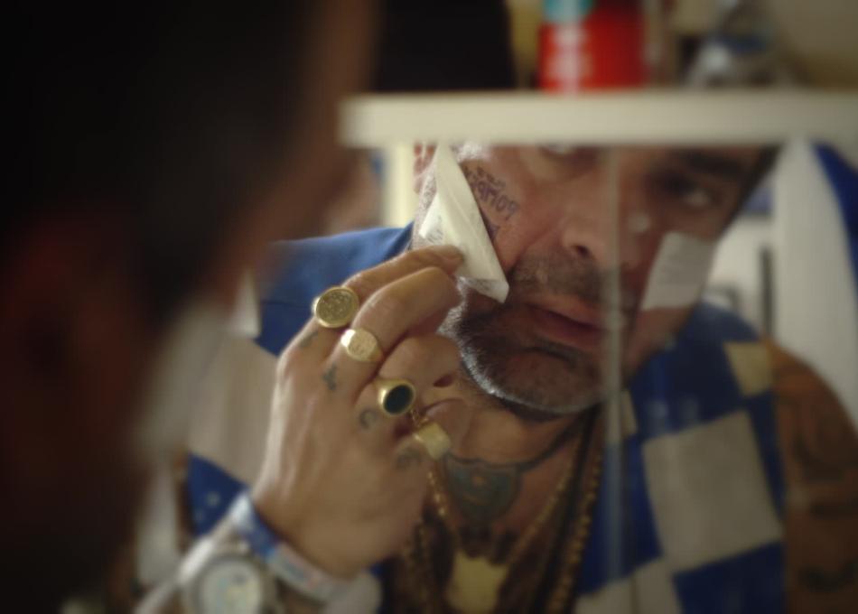 Football fan with tattoos putting on temporary tattoo in mirrow