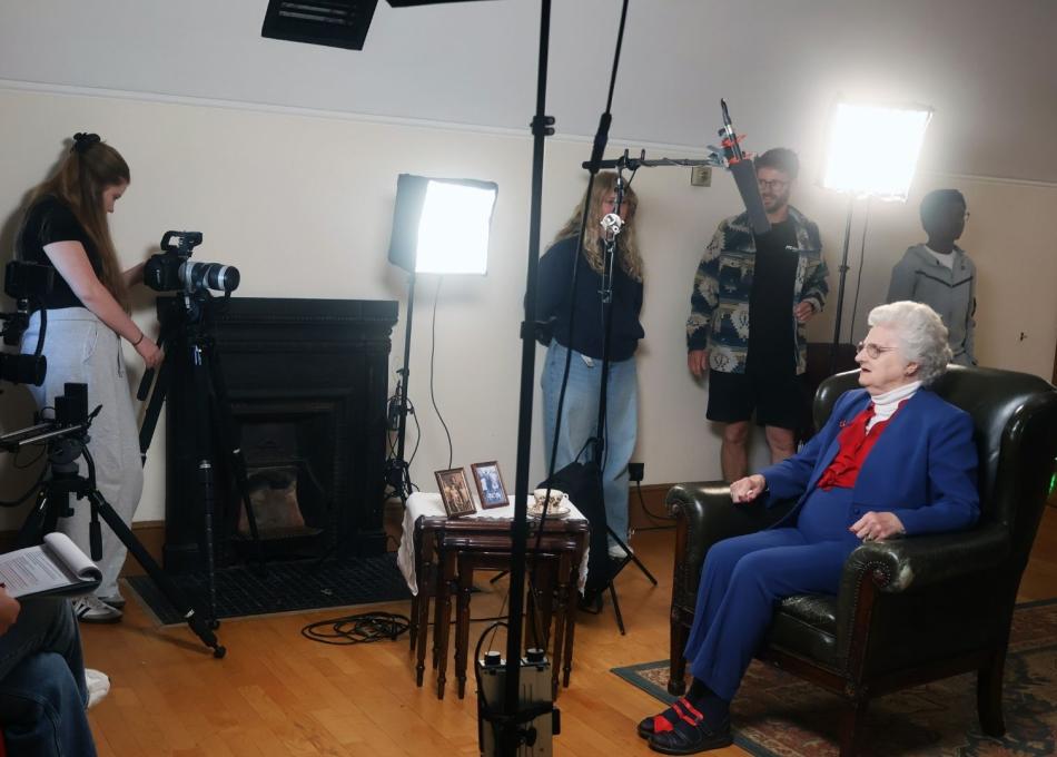 Student filmmakers interviewing an older lady in an arm chair