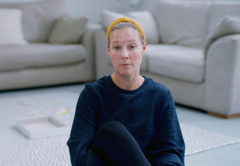 Lady sat o living room carpet wearing a yellow head band