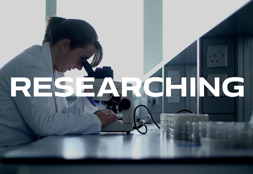Science student looking into microscope in lab