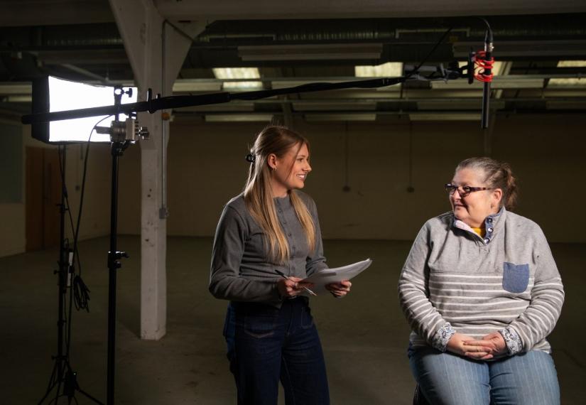 Female filmmaker preparing to interview a lady in a factory