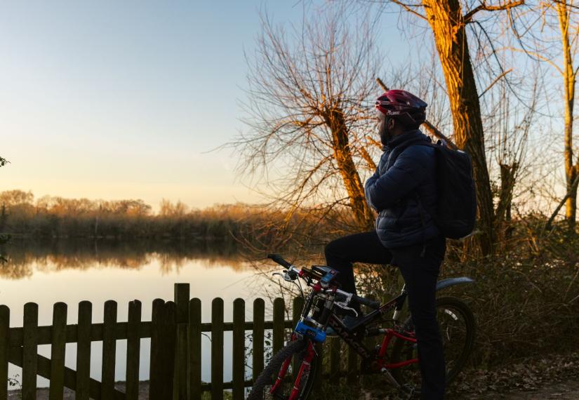 cyclist stopped on his bike and looking out over a lake in Wokingham