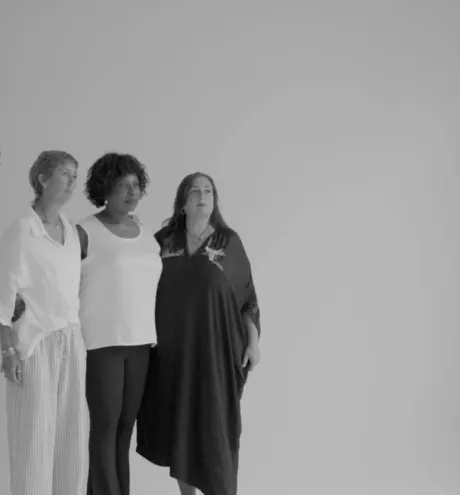 B&W photograph: Photographer shoots three women posing in a bright studio with a softbox.
