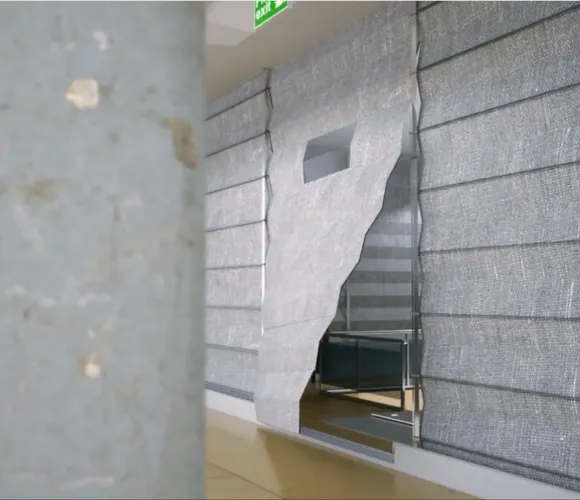 Hallway with a grey textured wall partially peeled away revealing layers, next to a beige marble column.