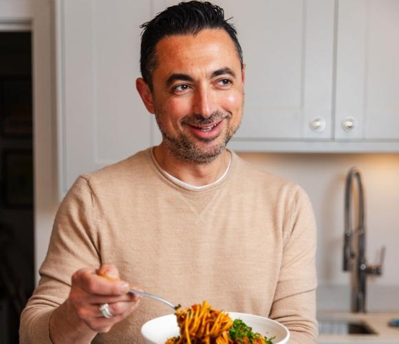 Celebrity chef Theo Michaels holding a bowl of spaghetti bolognese in his kitchen