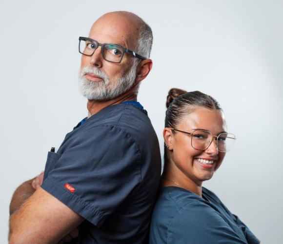 Two staff members posing back to back for a headshot