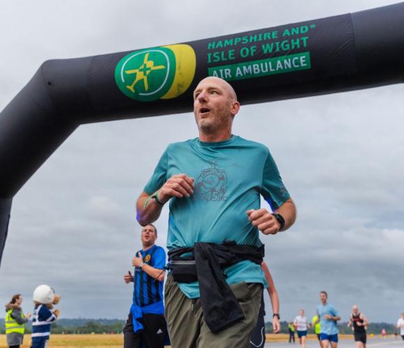 A runner crossing the finish line at the Hampshire and Isle of Wight Air Ambulance event