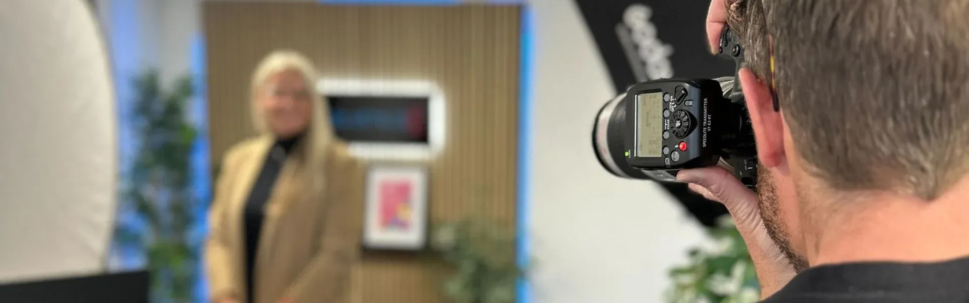 Photographer focused on shooting a woman's portrait in a studio, surrounded by lights.