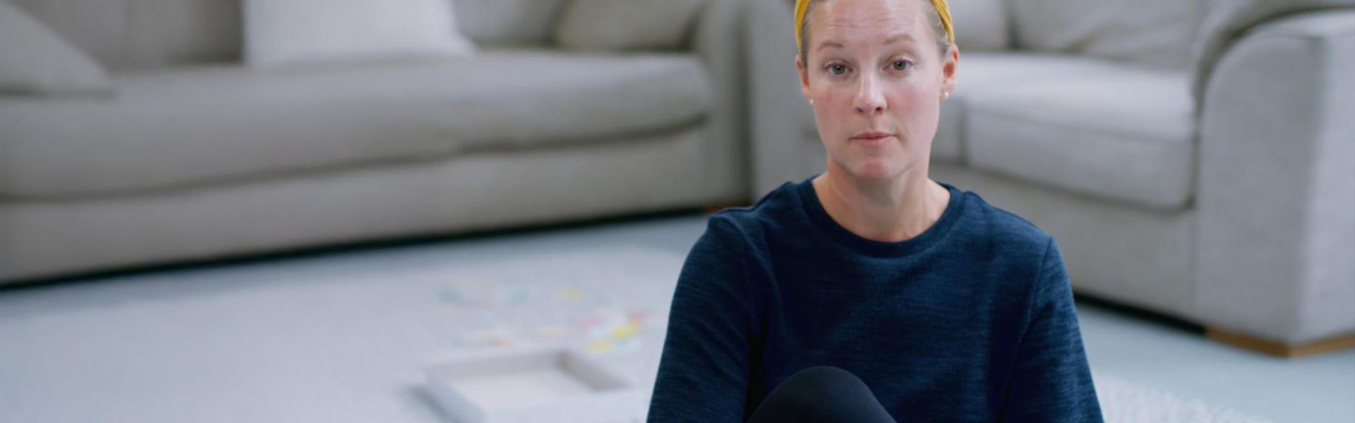 Lady sat o living room carpet wearing a yellow head band