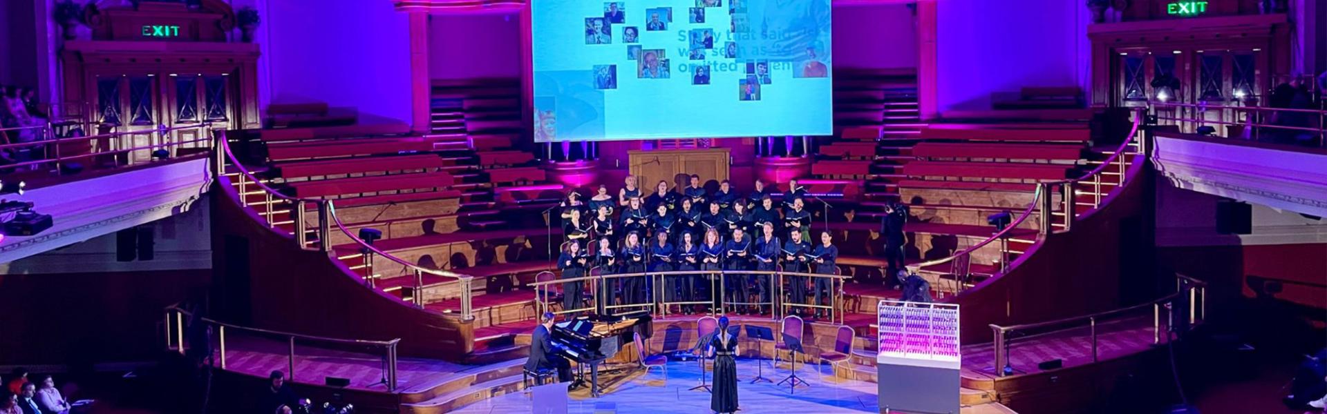 Stage with choir showing a film on a projector screen