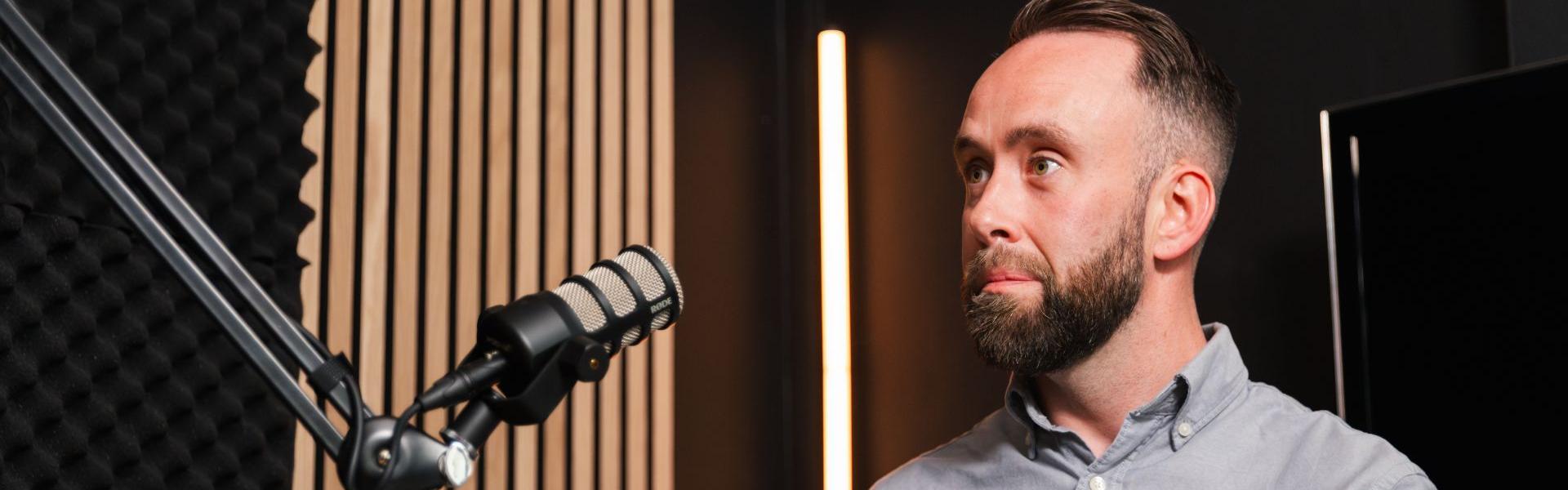 someone sat at a podcast microphone in a podcast recording studio